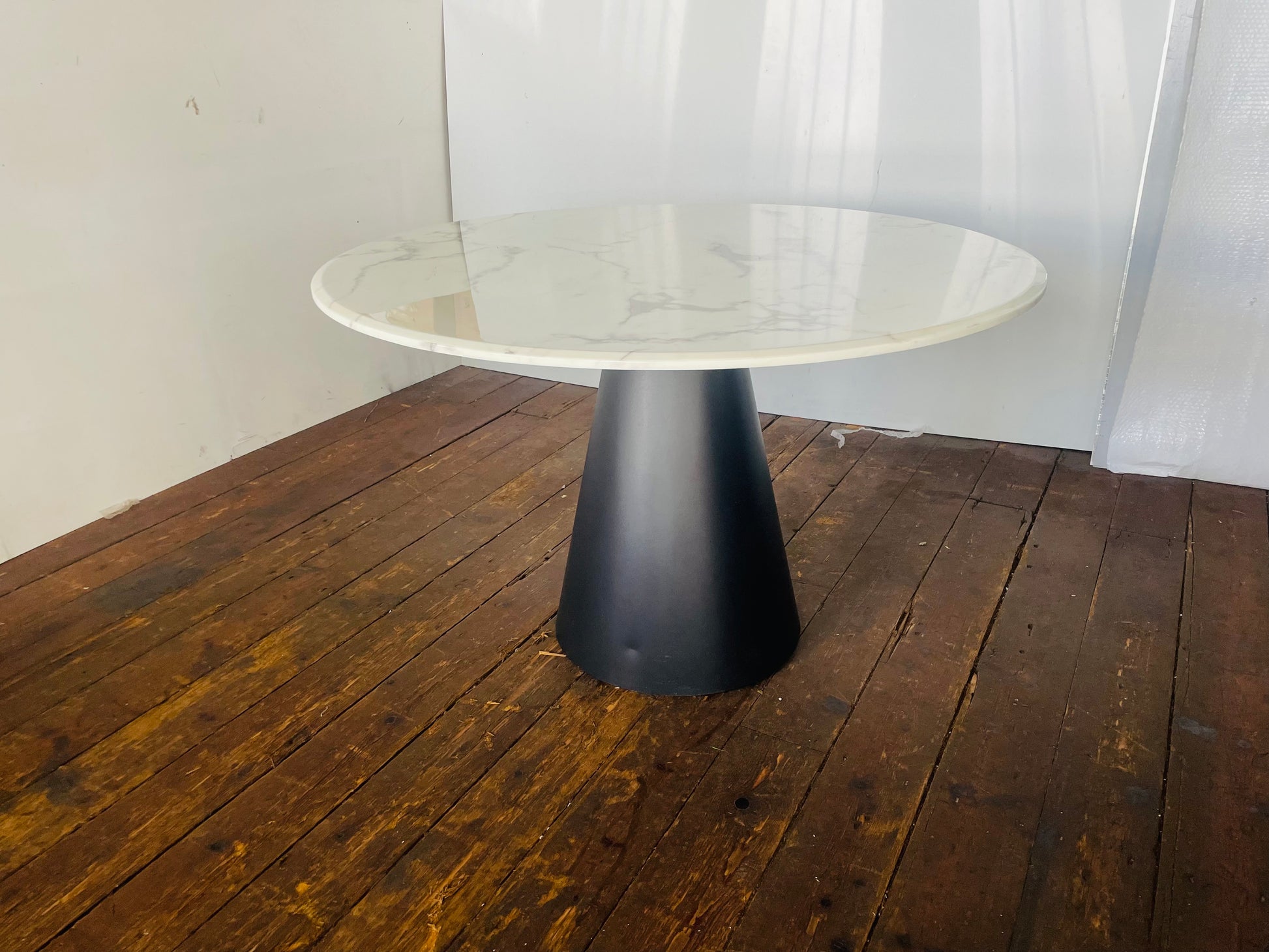 Richmond Degas 120cm round dining table featuring a sleek, smooth white faux marble top resting on a bold, conical matte black metal pedestal base