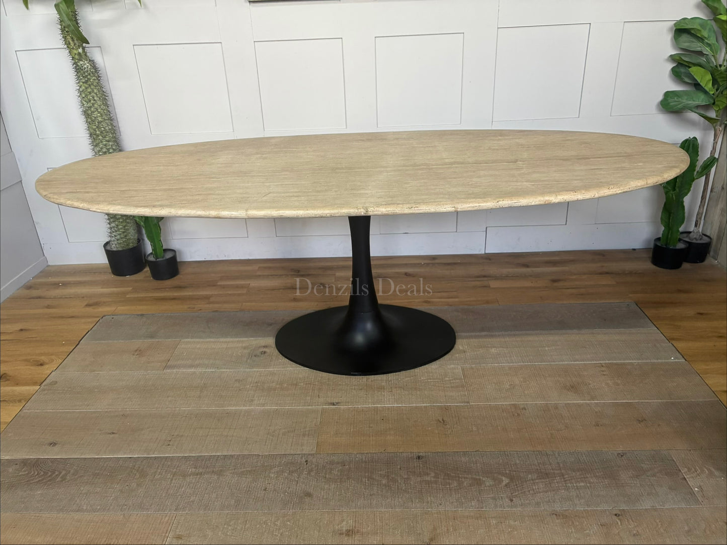 Richmond Interiors Hampton 8-seater dining table featuring a natural beige travertine stone oval top and modern black iron pedestal."