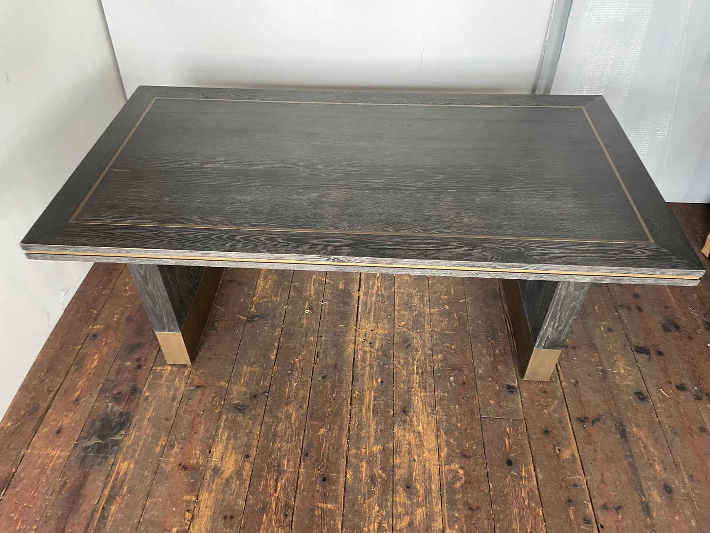 A small rectangular Richmond Interiors Hunter dining table featuring a black oak veneer tabletop with matte brushed gold metal legs and geometric corner inlay details. 