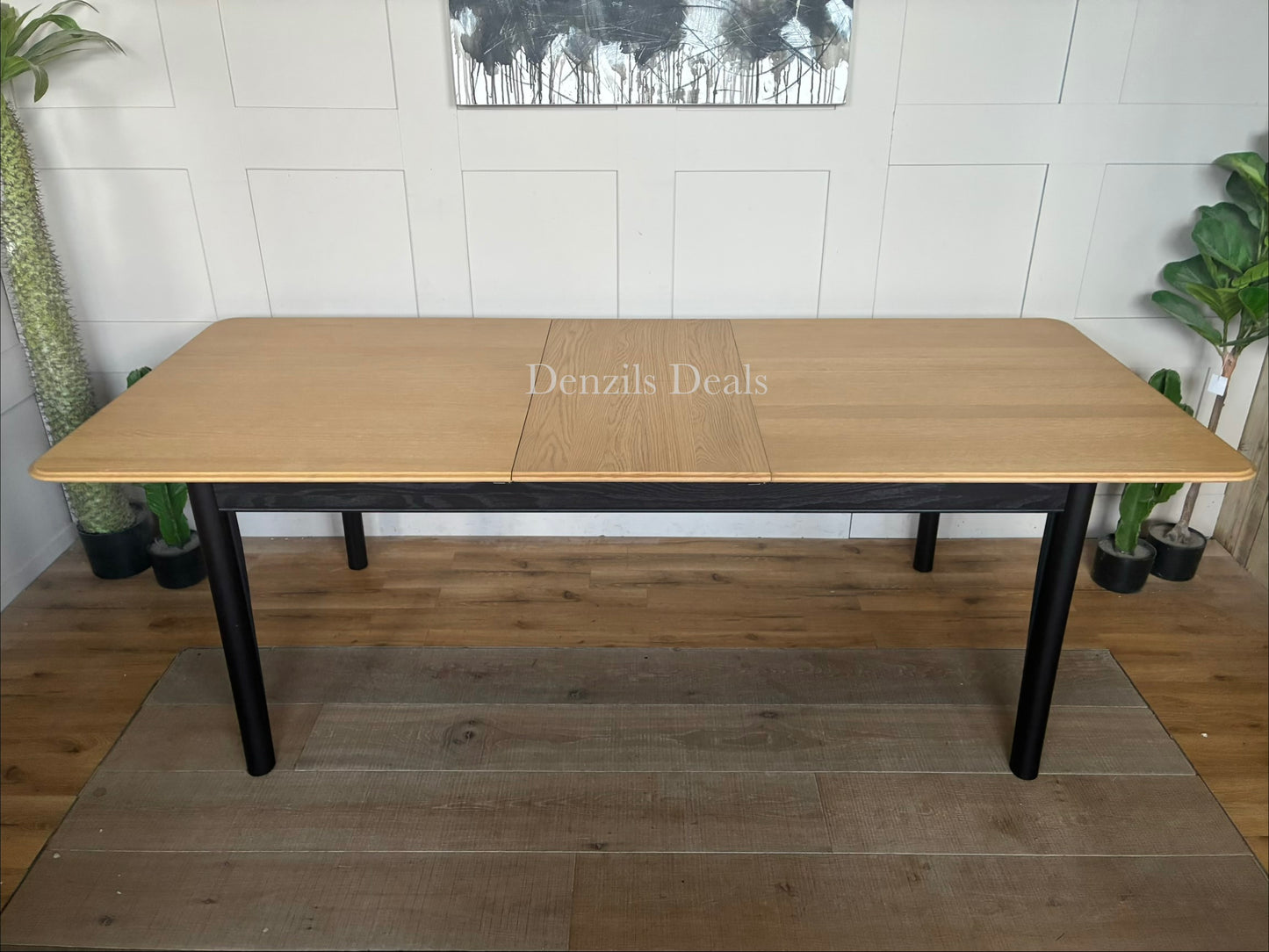 Modern John Lewis Stanton extending dining table featuring a natural light oak rectangular tabletop supported by angular, black metal or painted wooden legs.