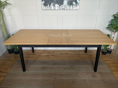 Modern John Lewis Stanton extending dining table featuring a natural light oak rectangular tabletop supported by angular, black metal or painted wooden legs.