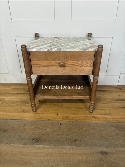 The Amelia Marble-Top Nightstand by Anthropologie features a smooth Toronto marble top, delicate spindled legs, an undermount shelf, and crafted oak woodgrain detailing.