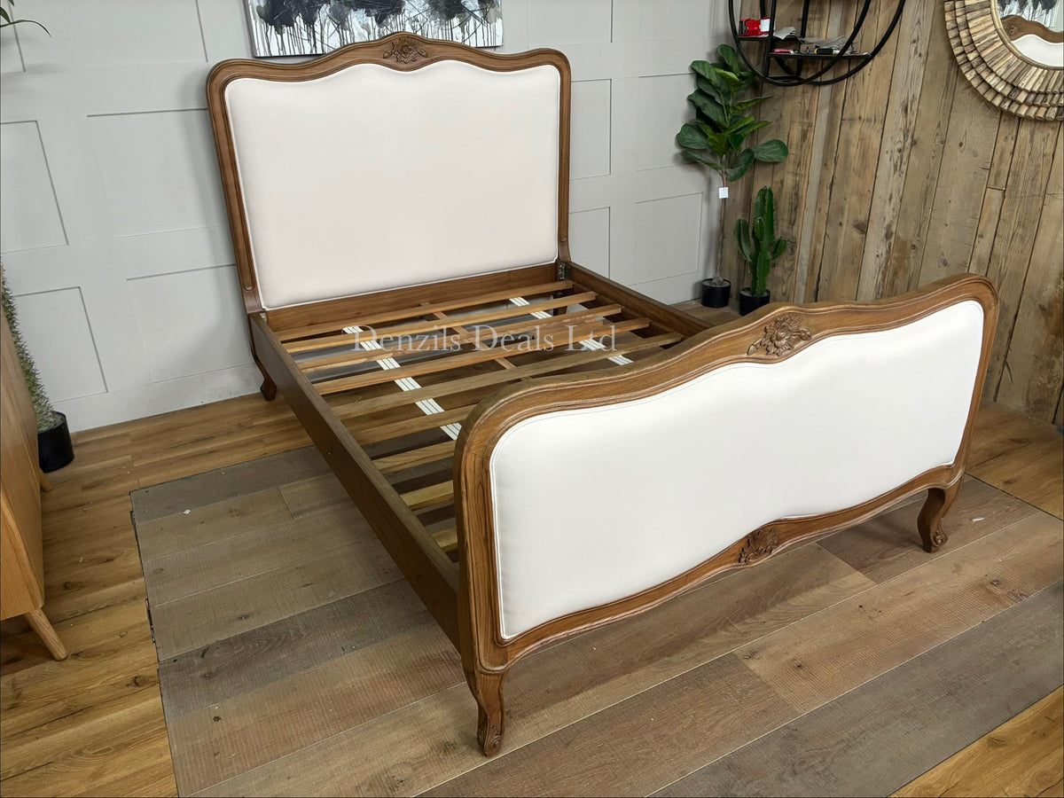 The Homesdirect365 Montpellier Antique French Style Bed frame, meticulously hand-crafted from solid Mindy wood. The bed showcases an elegant vintage design with a soft whitewash cream finish highlighting its natural wood grains. It features an ornately carved, subtly arched headboard and footboard, elegantly curved cabriole legs, and a sturdy slatted foundation layout