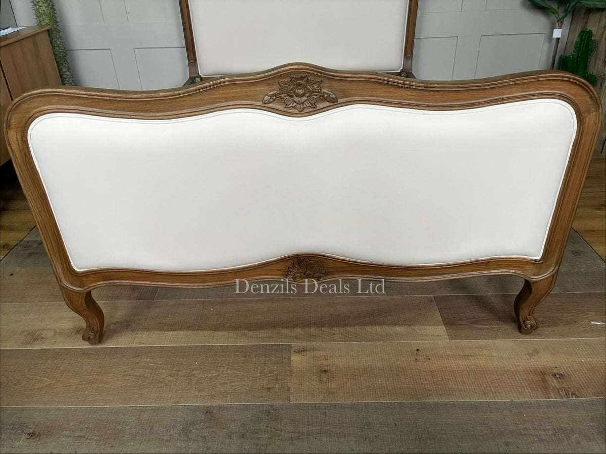 The Homesdirect365 Montpellier Antique French Style Bed frame, meticulously hand-crafted from solid Mindy wood. The bed showcases an elegant vintage design with a soft whitewash cream finish highlighting its natural wood grains. It features an ornately carved, subtly arched headboard and footboard, elegantly curved cabriole legs, and a sturdy slatted foundation layout