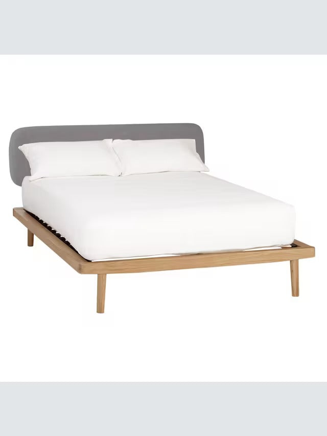 The John Lewis Bow king-size bed frame, crafted from natural grained solid oak and oak veneers, showcasing a soft upholstered fabric headboard and a low-profile, minimalist design."