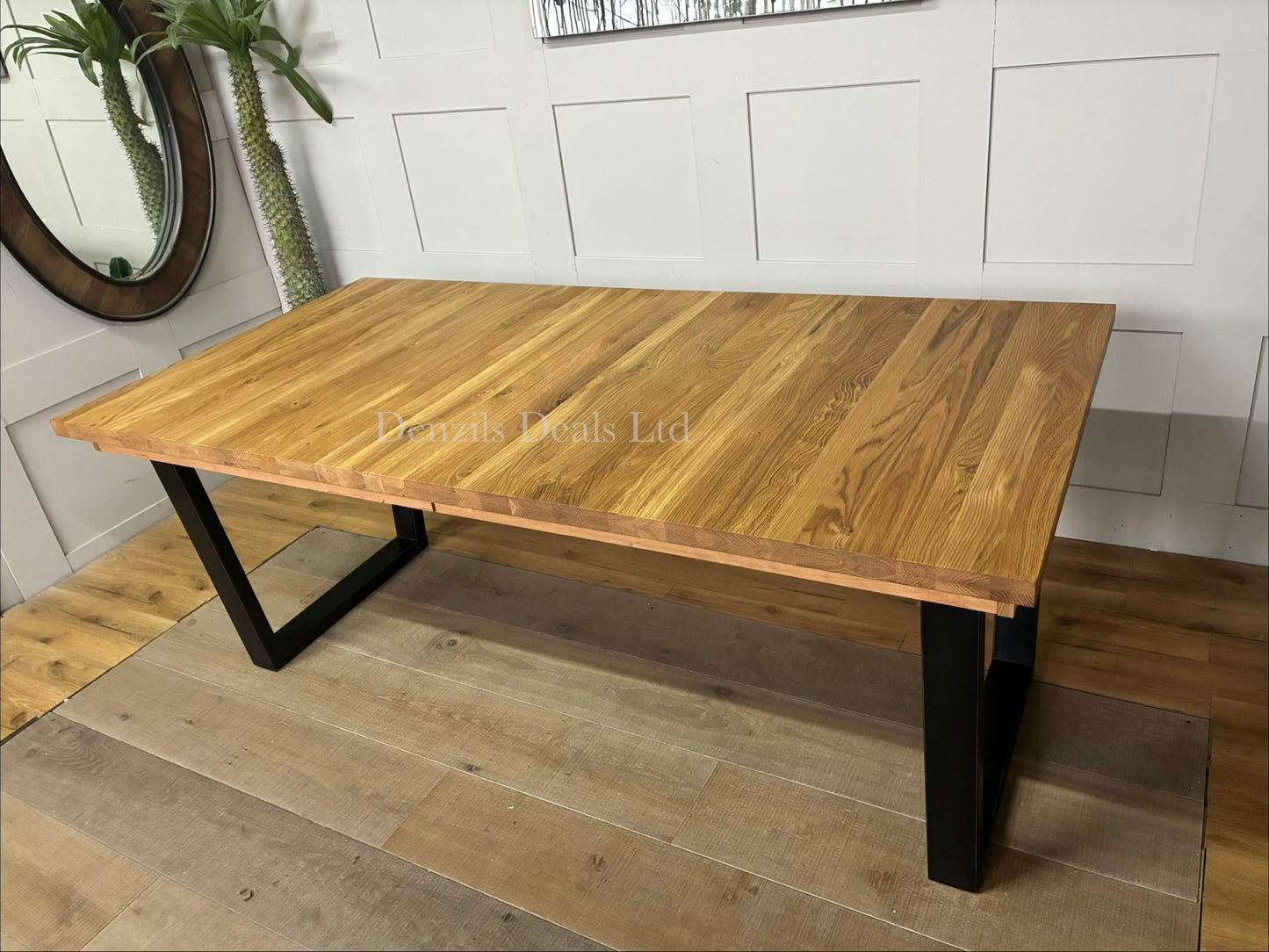The John Lewis Calia oak dining table shown fully extended to seat 10 people, highlighting the center extension leaf slot."