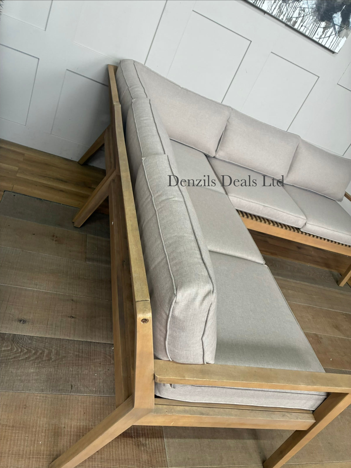 The John Lewis Mona 4-seater corner garden sofa arranged on an outdoor patio, showcasing its contemporary acacia wood slatted frame and textured natural fabric cushions
