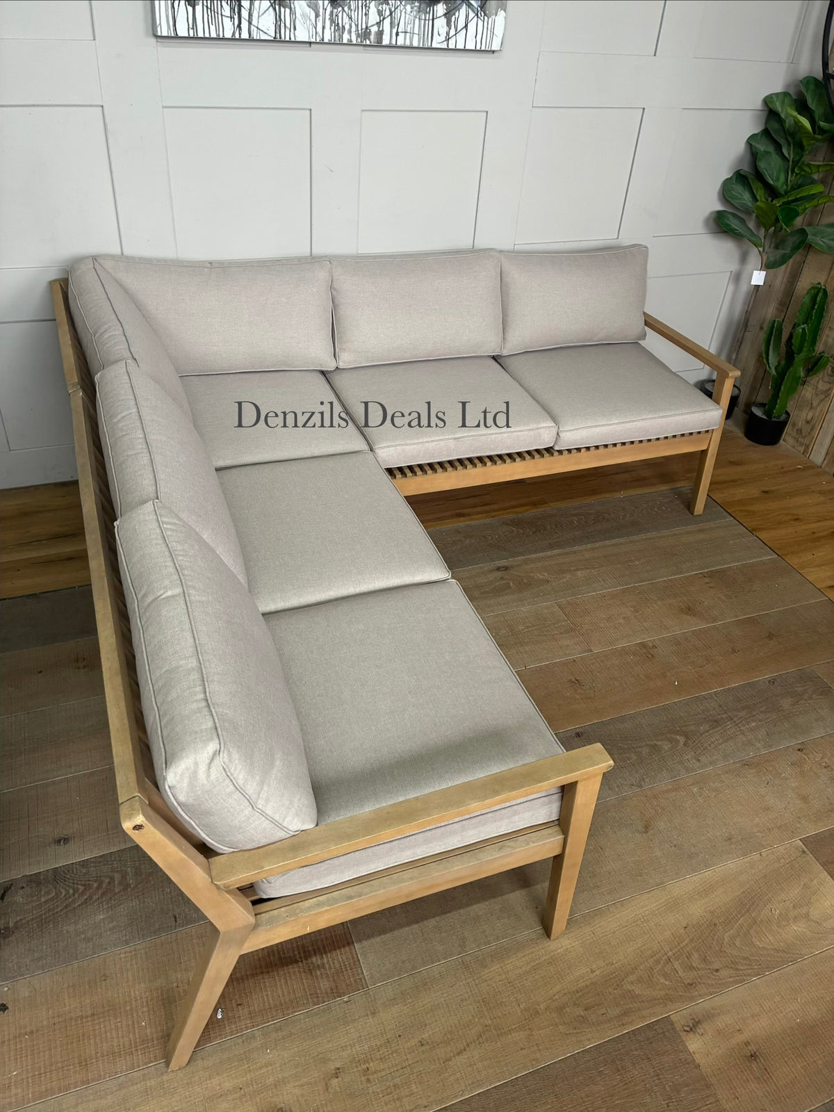 The John Lewis Mona 4-seater corner garden sofa arranged on an outdoor patio, showcasing its contemporary acacia wood slatted frame and textured natural fabric cushions