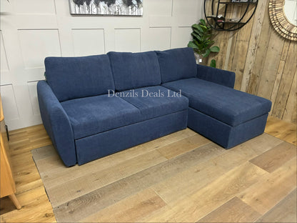 The John Lewis Sansa sofa bed fully extended into a large double bed, showing the main section pulled out alongside the stationary chaise section to form a wide, flat foam mattress sleeping area.