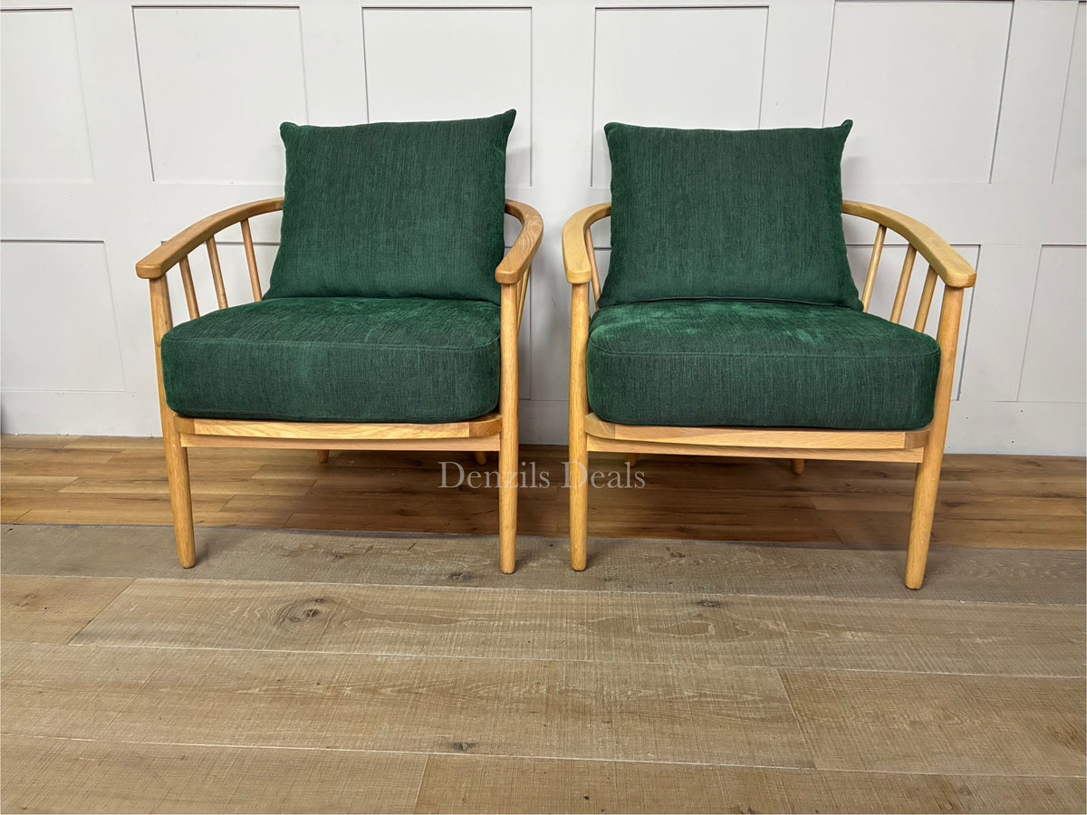 Two mid-century style John Lewis Frome armchairs side by side, featuring rich forest green fabric, plush foam cushions, and a curved silhouette cradled by a light natural oak frame.