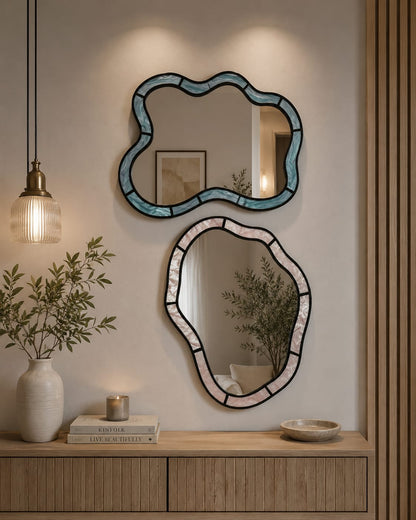 Two vertically oriented, rectangular wall mirrors featuring wavy, "squiggle" frame. The mirror on the left has a light, pearlescent lilac purple frame, while the mirror on the right has a matching pearlescent soft blue frame, both displaying a subtle, glossy iridescence.