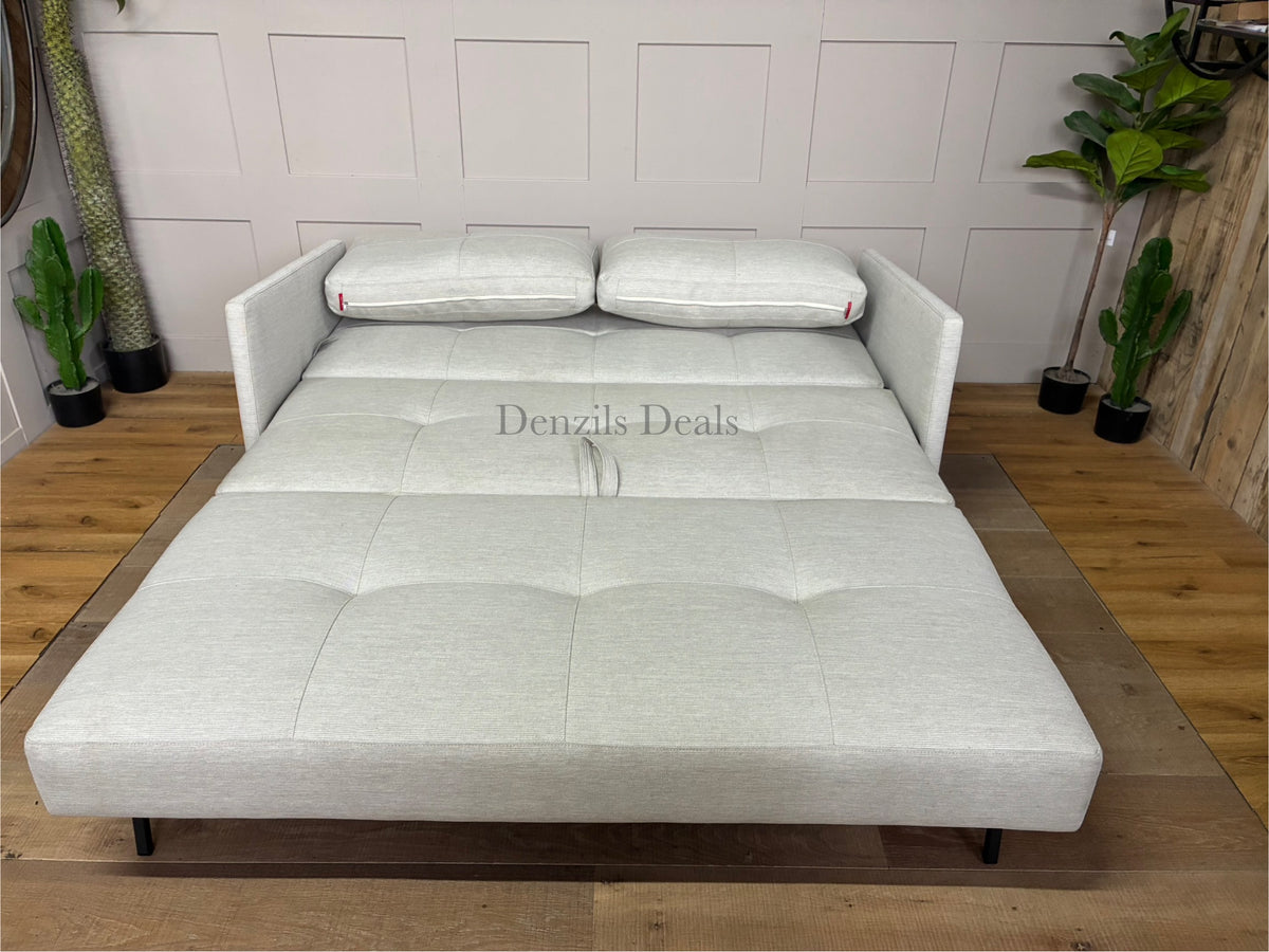 Scandinavian-style sofa bed in textured beige fabric with oak legs, shown as a cozy, compact living room seat. Unfolded view