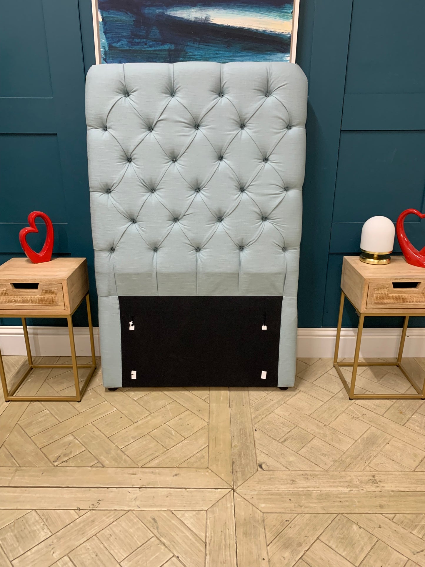 Upholstered single headboard in a pale, dusty blue featuring Loaf's signature pillowy cushion design and a tall profile. 