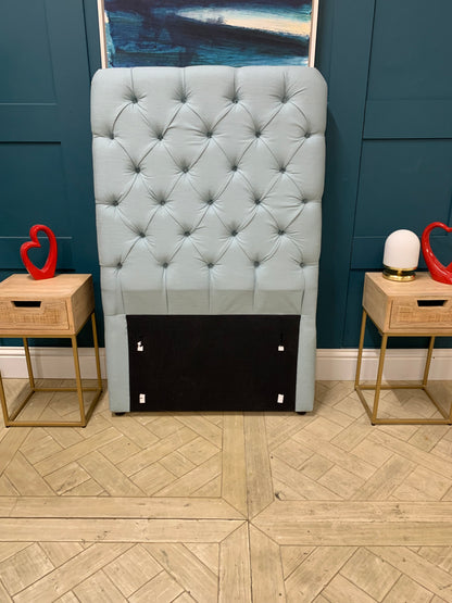 Upholstered single headboard in a pale, dusty blue featuring Loaf's signature pillowy cushion design and a tall profile. 