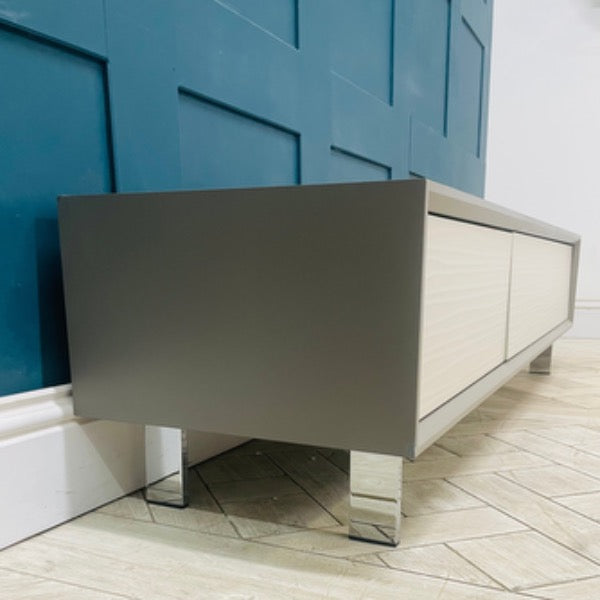 Wide Dante TV cabinet in a modern living room setting, supporting a large screen television. Side view 