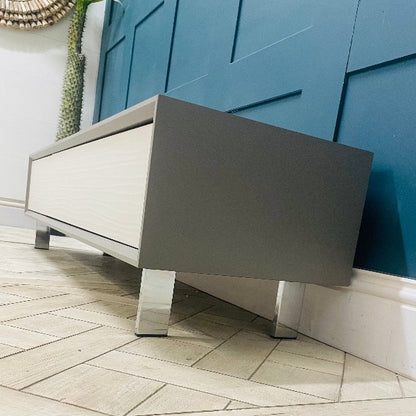 Wide Dante TV cabinet in a modern living room setting, supporting a large screen television. Side view 