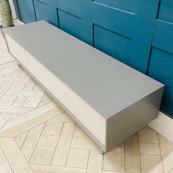 Wide Dante TV cabinet in a modern living room setting, supporting a large screen television. Side view 