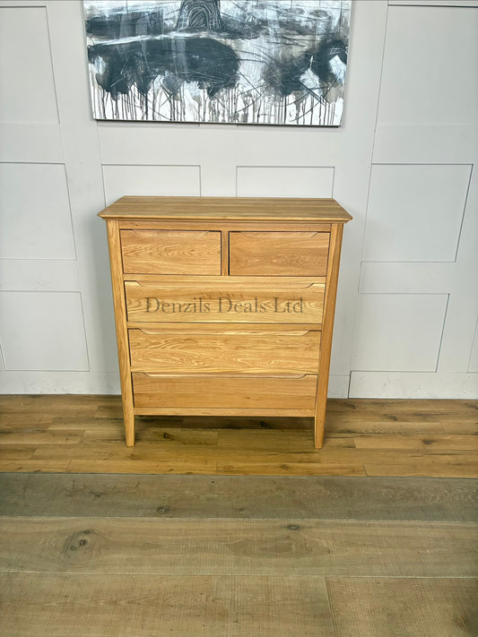 A front view of a contemporary mid-century style 2+3 chest of drawers made from light natural solid oak, featuring rounded corners, tapered legs, and flat-fronted drawers with clean recessed groove handles