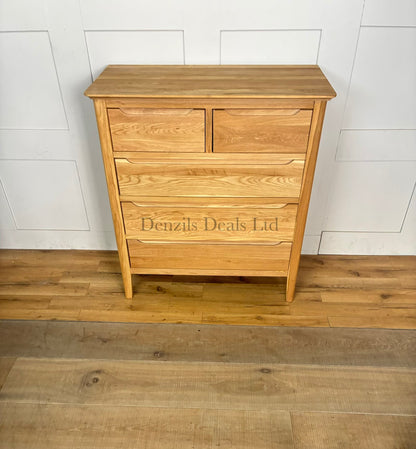 A front view of a contemporary mid-century style 2+3 chest of drawers made from light natural solid oak, featuring rounded corners, tapered legs, and flat-fronted drawers with clean recessed groove handles