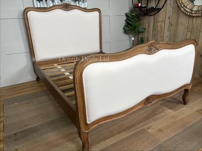 An antique French style wooden bed frame crafted from natural solid Mindy wood, featuring a light whitewash finish, ornate hand-carved detailing, a curved headboard, and a slatted base