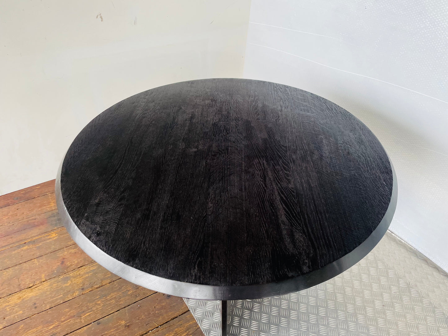 A round, black oak wood Anthropologie Iris dining table featuring a modern, sculptural silhouette with curved lines
