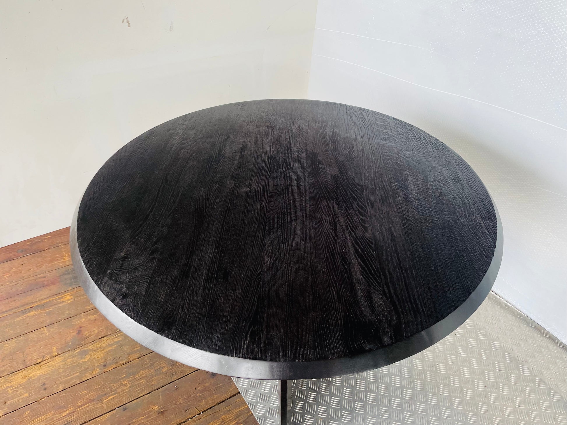 A round, black oak wood Anthropologie Iris dining table featuring a modern, sculptural silhouette with curved lines