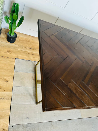 A vintage-inspired, dark wood herringbone dining table from Dutchbone set in a warmly lit