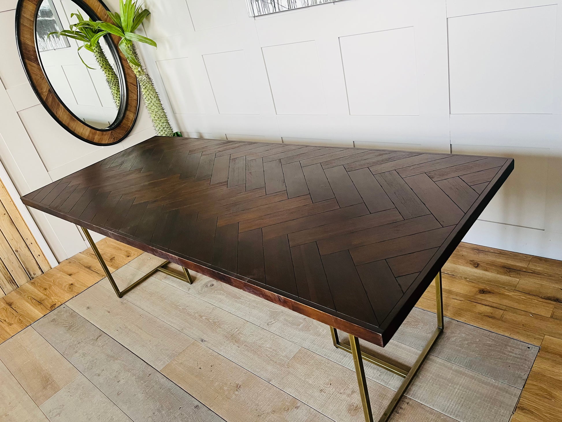 A vintage-inspired, dark wood herringbone dining table from Dutchbone set in a warmly lit