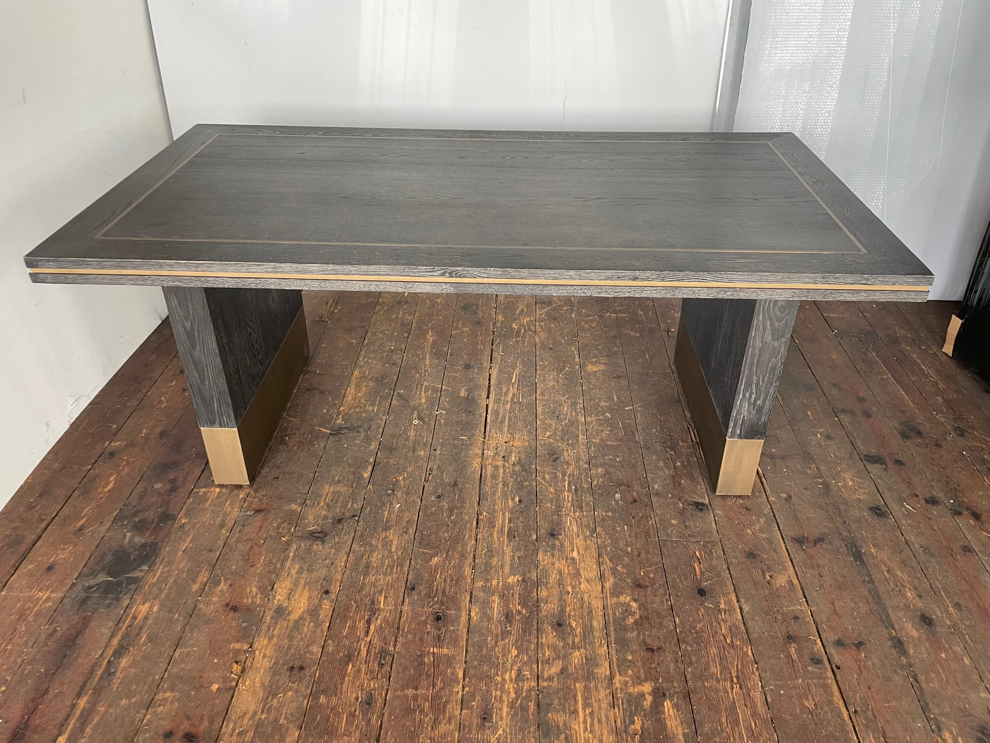 A small rectangular Richmond Interiors Hunter dining table featuring a black oak veneer tabletop with matte brushed gold metal legs and geometric corner inlay details. 