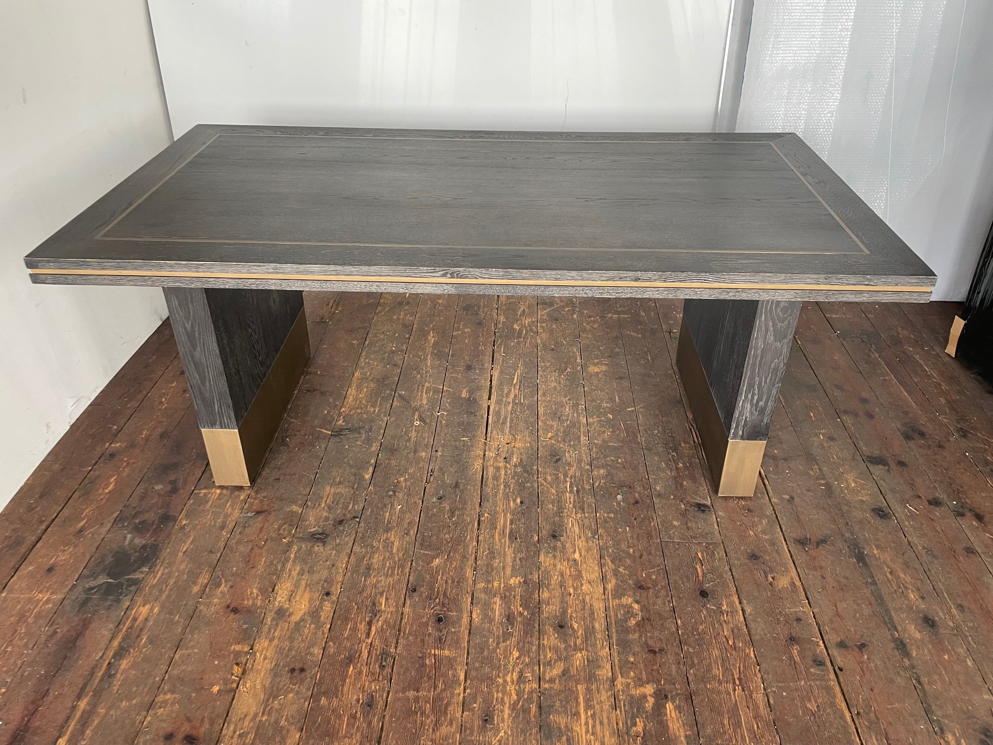 A small rectangular Richmond Interiors Hunter dining table featuring a black oak veneer tabletop with matte brushed gold metal legs and geometric corner inlay details. 