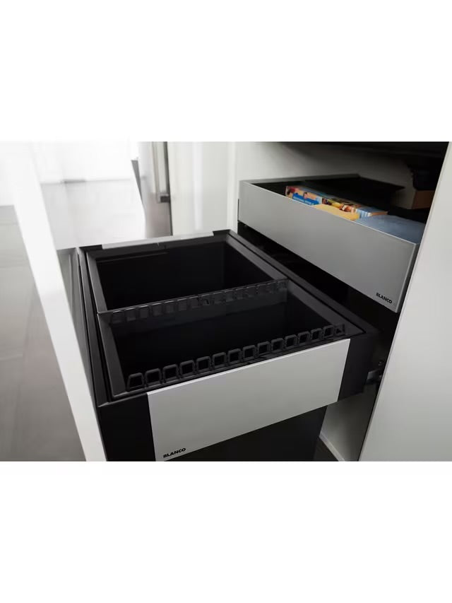 A BLANCO Select under-counter pull-out kitchen bin with two grey compartments, shown partially extended from a minimalist dark cabinet to reveal its 38-litre waste separation system. 