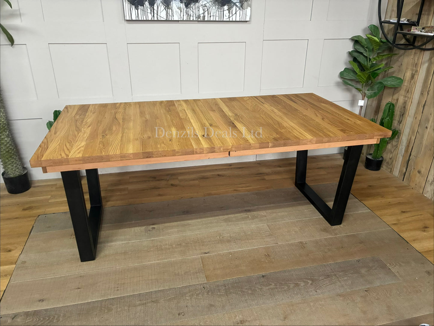 An industrial-style John Lewis Calia rectangular extending dining table. The table features a light-colored, wire-brushed solid oak top made of individual wood slats, supported by thick, angular black iron legs.