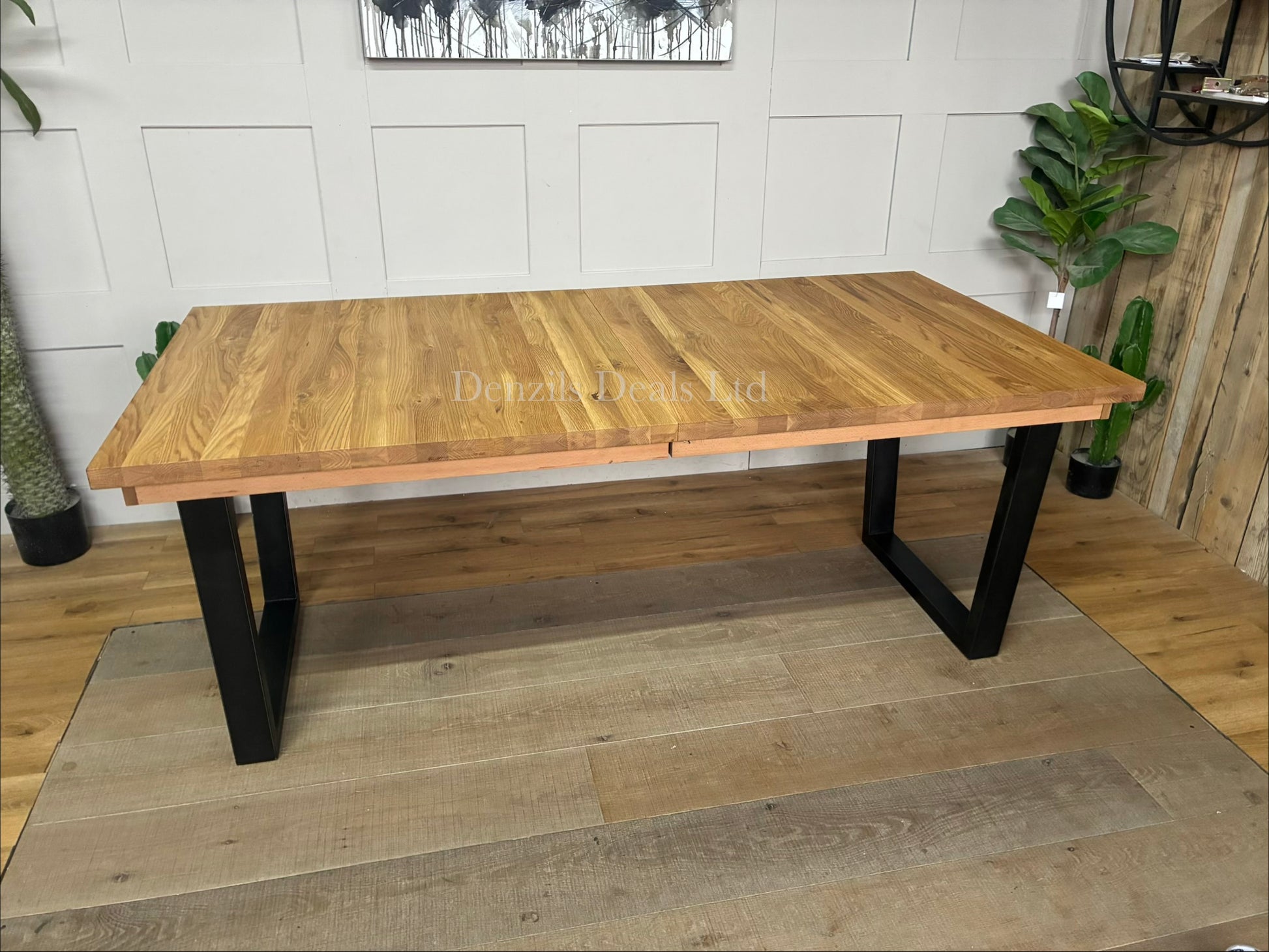 An industrial-style John Lewis Calia rectangular extending dining table. The table features a light-colored, wire-brushed solid oak top made of individual wood slats, supported by thick, angular black iron legs.
