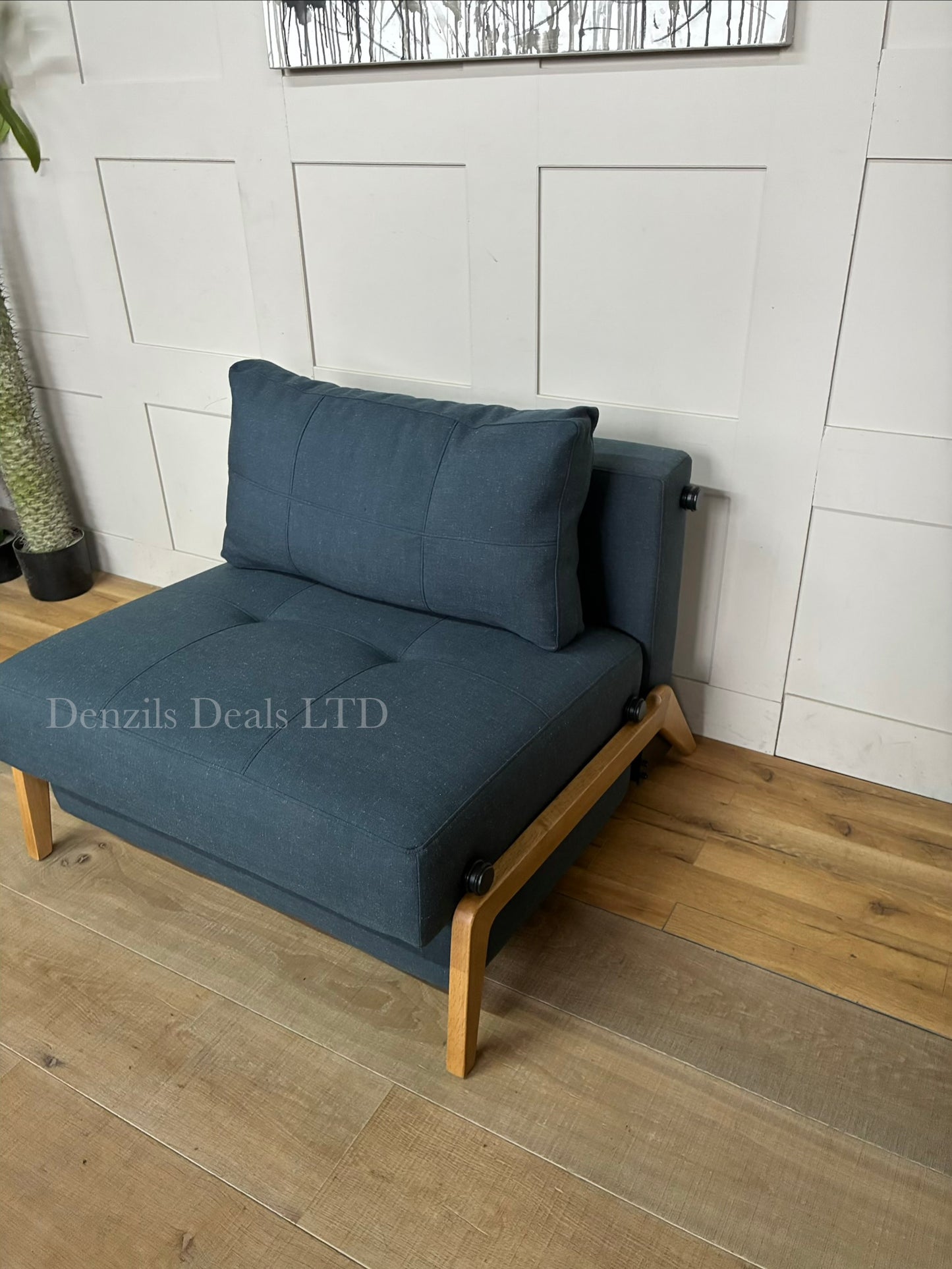 A compact, modern armchair bed by Innovation Living upholstered in dark Nist Blue fabric, featuring a tufted back cushion and sleek metal legs.