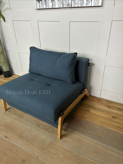 A compact, modern armchair bed by Innovation Living upholstered in dark Nist Blue fabric, featuring a tufted back cushion and sleek metal legs.