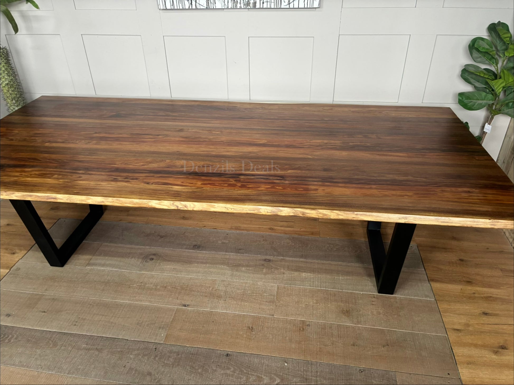 A modern industrial Bartolo dining table by Nick Scali. The rectangular table features a thick, warm-toned Tasmanian Blackwood tabletop with organic, wavy live edges that highlight the natural wood grain. The top rests on two heavy-duty, black powder-coated steel sleigh-style legs at either end, blending rustic warmth with a clean, industrial look