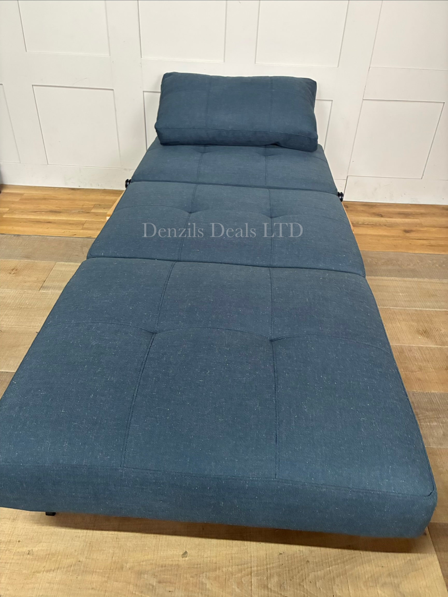 "A modular Innovation Living Cubed 90 armchair shown in a deep Nist Blue shade. The compact armchair folds out seamlessly from a stylish single seat into a flat, supportive twin-sized sleeper bed for guests."