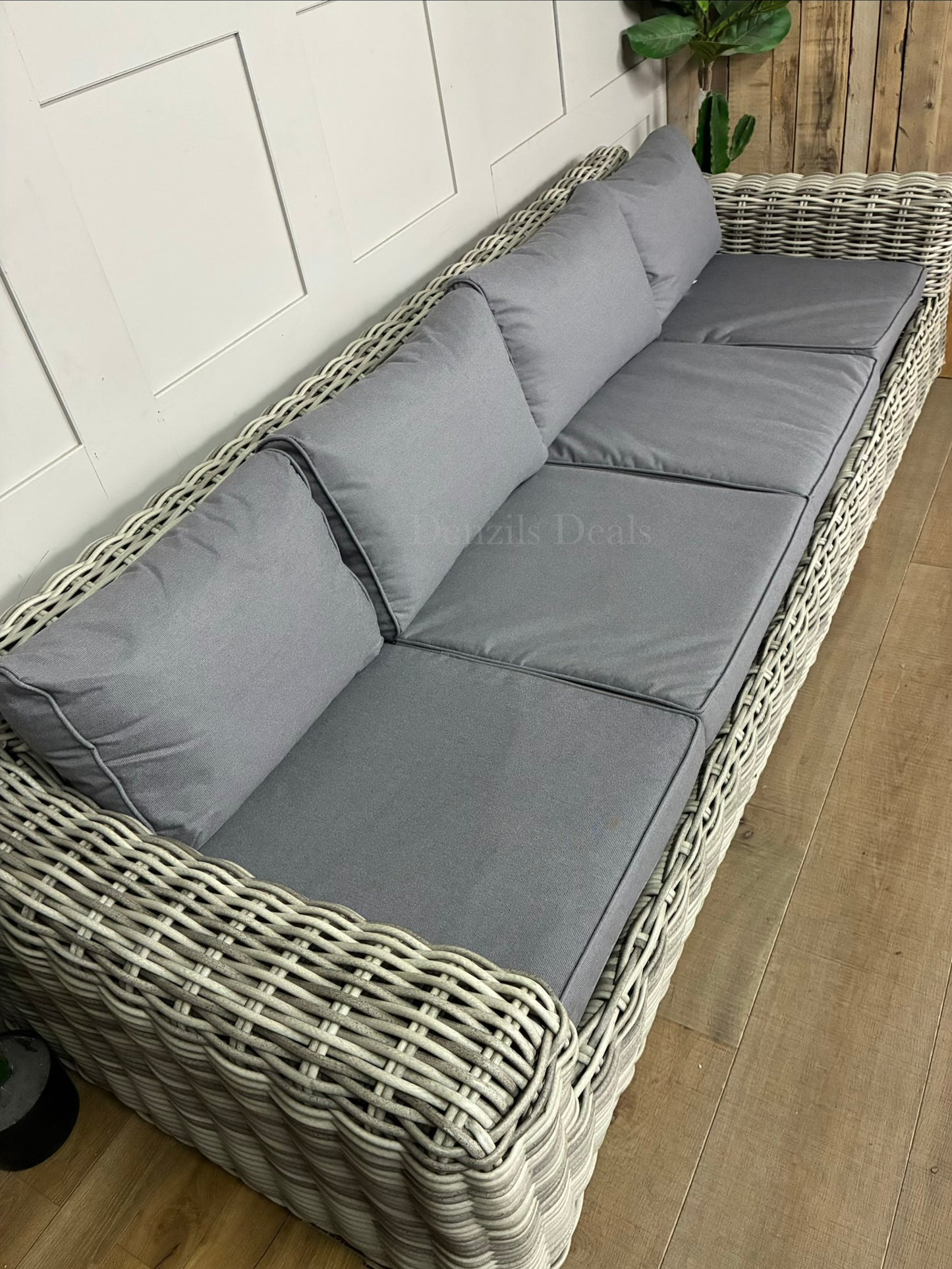 A chunky natural rattan 3-seater garden sofa with deep, neutral-toned outdoor cushions, top view