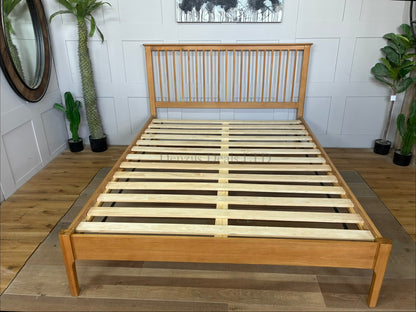 A natural solid oak and oak veneer king-size bed frame featuring a traditional Shaker-style panelled headboard with vertical spindles, clean horizontal lines, tapered wooden legs, and a low foot end showcasing a warm natural wood grain finish