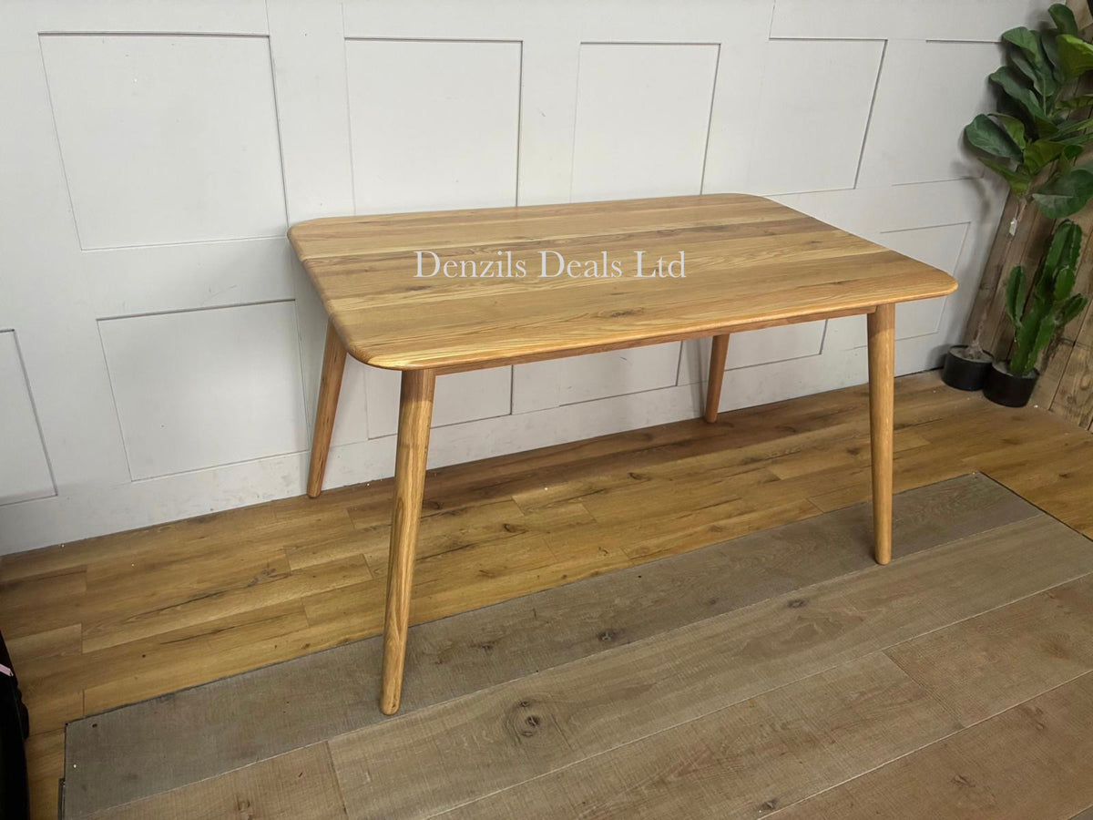 A contemporary rectangular dining table from the John Lewis Greenwood collection. The table is made of solid oak and premium veneers with a smooth Bianco oil clear coat. It highlights a minimalistic mid-century design with subtly tapered legs and a natural, light wood finish