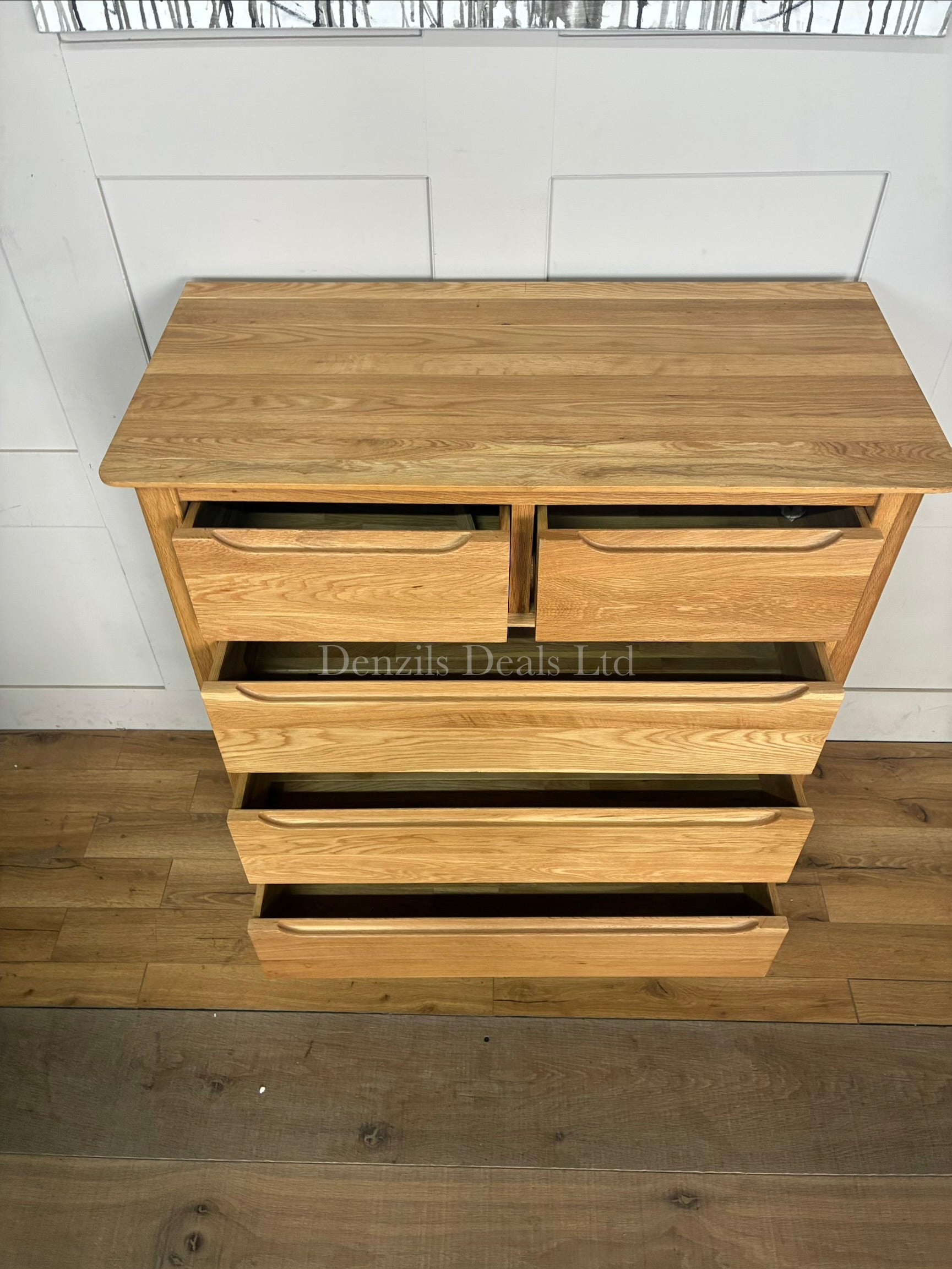 A tall, slender Copenhagen 5-drawer tallboy chest of drawers from Oak Furnitureland, constructed from 100% solid natural oak. Shows five vertically stacked drawers with recessed handle cutouts, softly rounded top corners, and short tapered legs