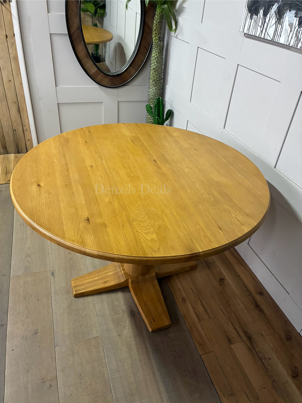 A bright dining room setting featuring the round Oak Furnitureland Henley natural oak pedestal table, surrounded by upholstered high-back dining chairs on a neutral area rug